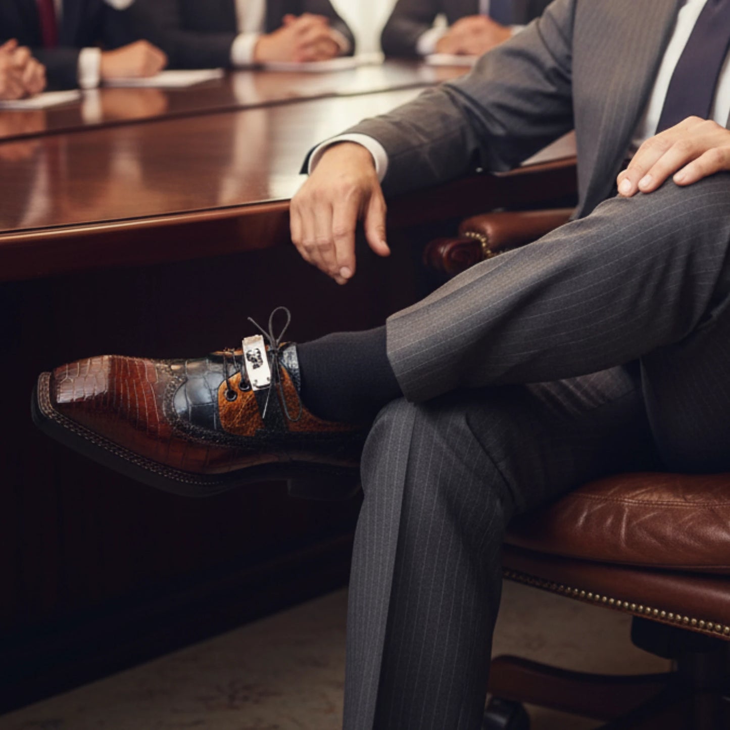 Man in a suit wearing nile crocodile Leather Dress Shoes sitting in an office chair 