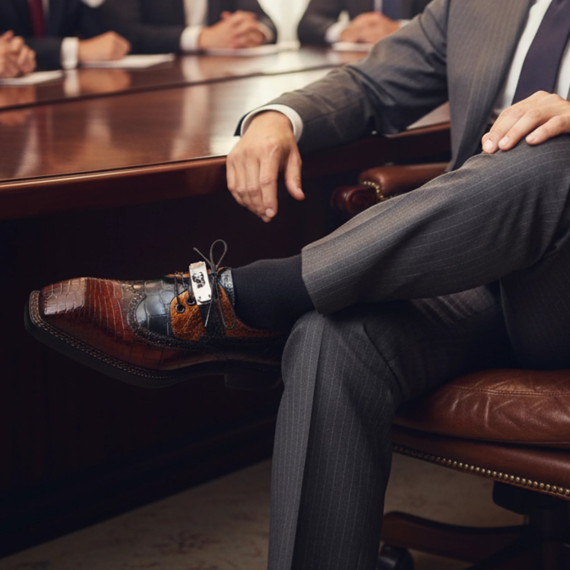 Man in a suit wearing nile crocodile Leather Dress Shoes sitting in an office chair 
