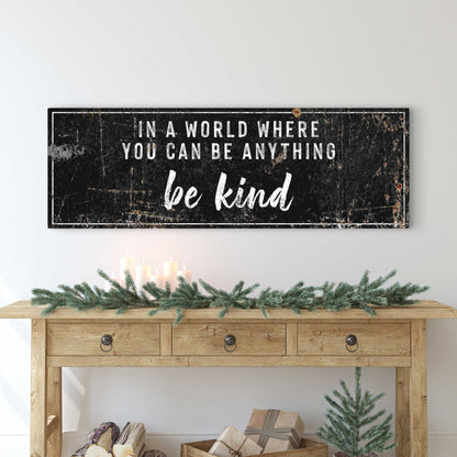 Be Kind canvas sign in the black style with white letters, above a wood console with a pine garland