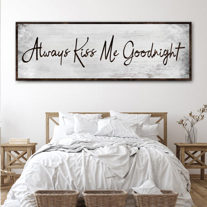 Wide canvas sign with Always Kiss Me Goodnight in black handwritten script on a pale gray ground, hung above a white bed