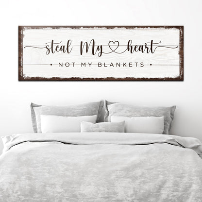 Steal My Heart Not My Blankets canvas sign in the white style with a dark worn edge, above a white bed
