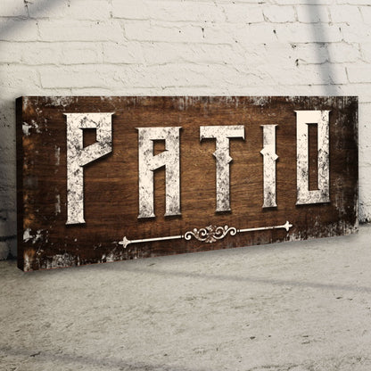 Angled close-up of the Patio canvas sign leaning against a white brick wall, showing its wrapped edge
