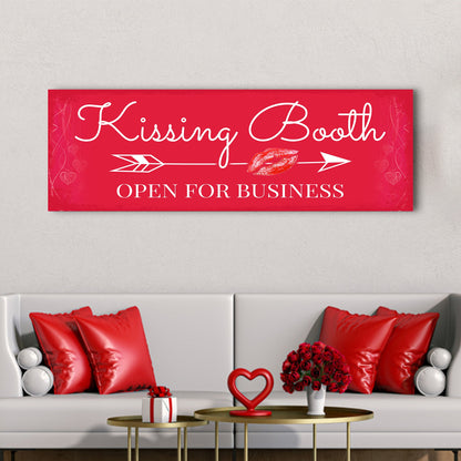 Long red canvas sign with white script Kissing Booth, an arrow and a lipstick kiss, above a white sofa with red pillows