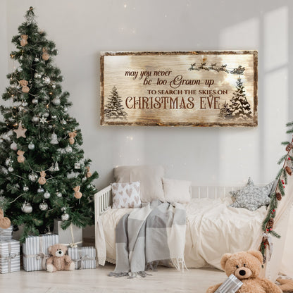 Rustic tan canvas sign with a Santa sleigh, snowy pines and a Christmas Eve saying, on a wall beside a decorated tree