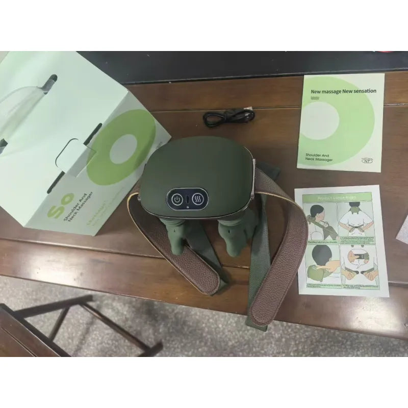 Neck and shoulder massager with packaging, user manual and charging cable displayed on a table.