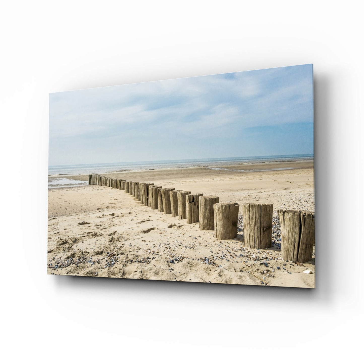 Beach glass wall art with driftwood groyne posts on pale sand shoreline