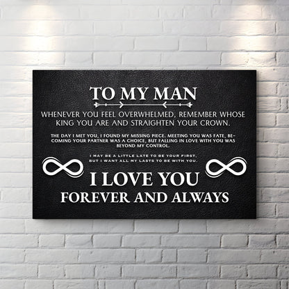 Black canvas sign with white text reading To My Man, a love message and two infinity symbols, on a white brick wall