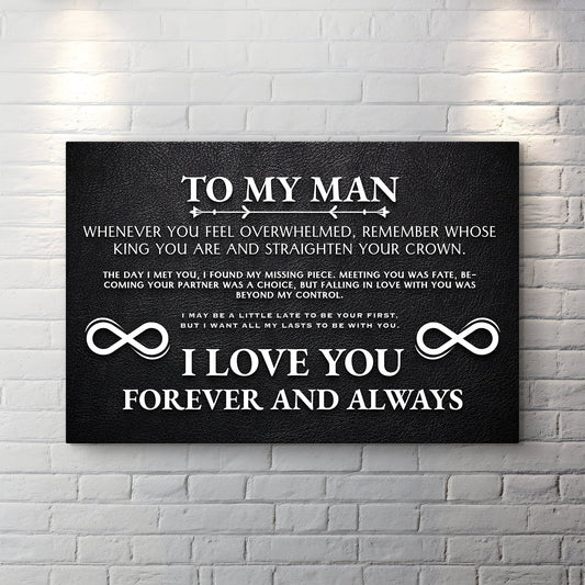 Black canvas sign with white text reading To My Man, a love message and two infinity symbols, on a white brick wall