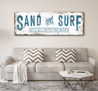 Sand and Surf sign in Style 2 with a rust-brown weathered edge, above a beige sofa