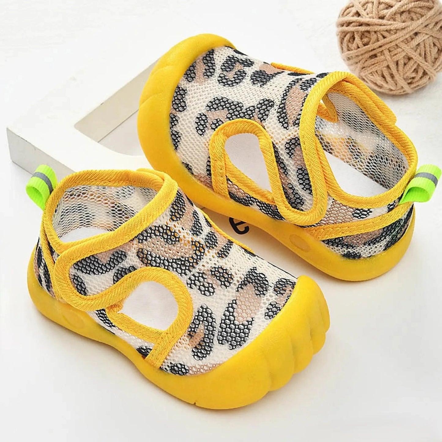 Pair of grey baby water shoes with leopard stripes on a white background