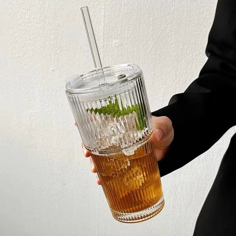 Person holding aesthetic glass drinking cup with reusable straw