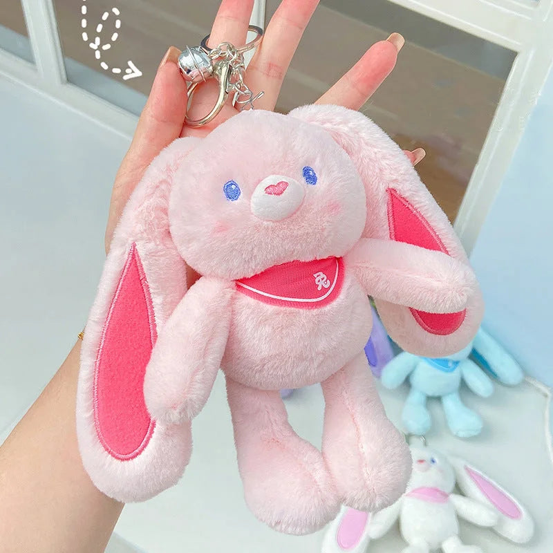 Pink rabbit plush keychain with hot pink inner ears, silver lobster clasp, and stretchy legs shown with hand