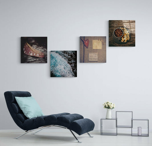 Wave, coffee, heart and leaf glass panels in a staggered cluster on a pale wall above a navy chaise lounge