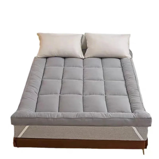 Quilted mattress topper pad on queen bed in grey with elastic corner straps
