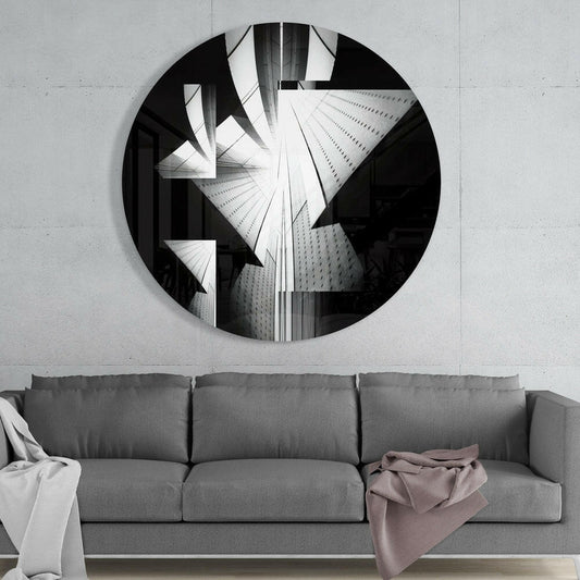 Black and white skyscraper round glass wall art above a gray sofa with white and mauve throws on a pale concrete wall