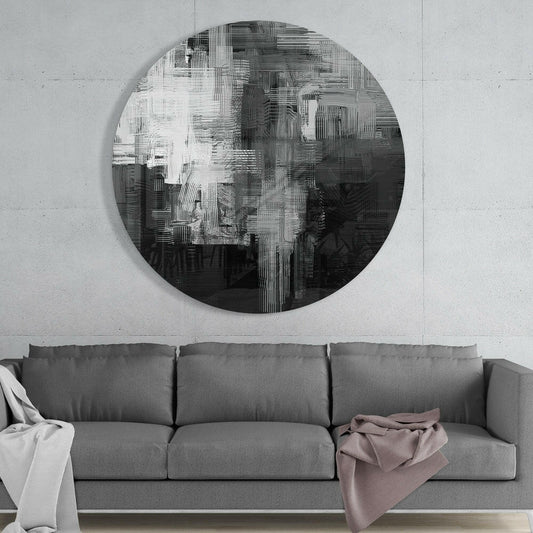 Black and white brushstroke round glass wall art above a gray sofa with white and pink throws