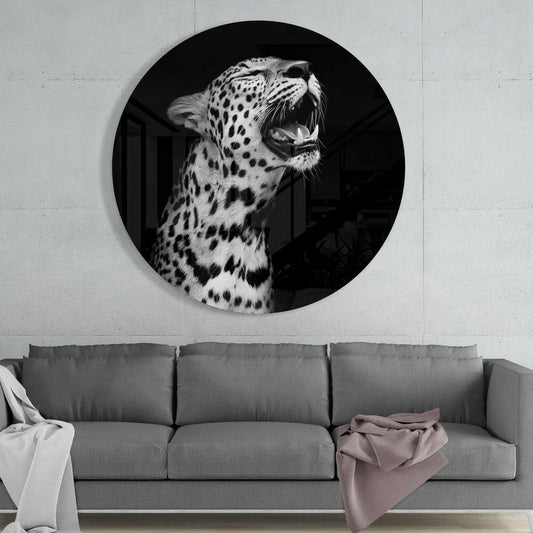 Yawning leopard round glass wall art above a gray sofa with white and mauve throws