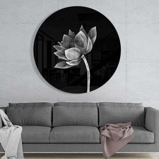 Monochrome lotus flower round glass wall art above a gray sofa with draped throws on a pale concrete wall