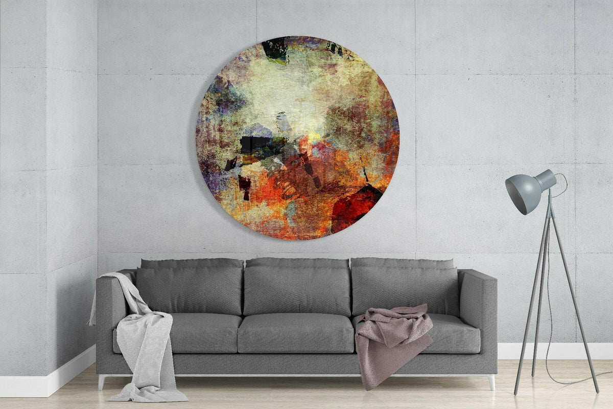 Rustic earth grunge abstract round glass wall art above a gray sofa beside a gray tripod floor lamp on a pale concrete wall