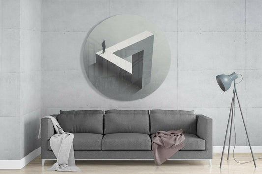 Impossible triangle round glass wall art above a gray sofa beside a tripod floor lamp on a pale concrete wall
