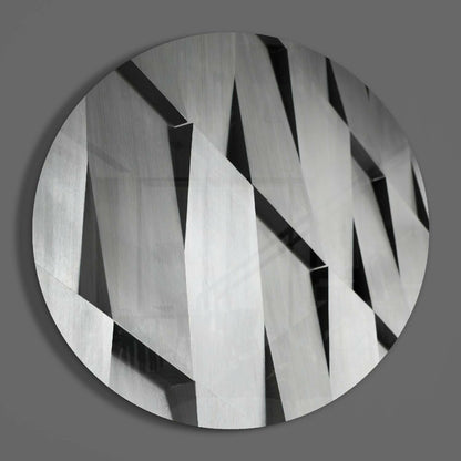Silver geometric slats round glass wall art on a plain gray wall