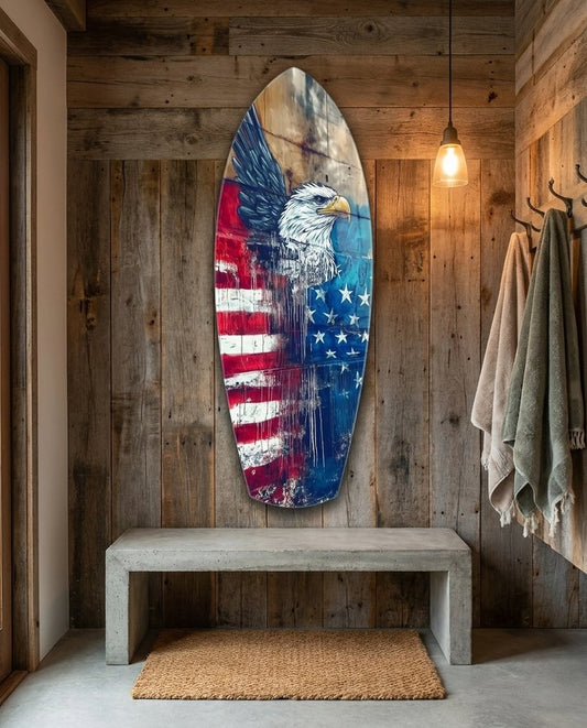 Eagle and flag surfboard glass wall art on a barn wood wall above a concrete bench beside hanging towels