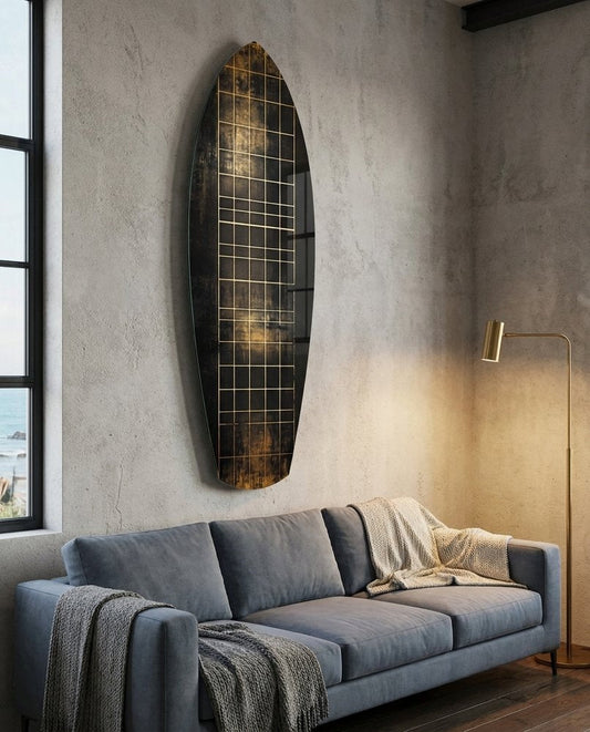 Black and gold grid surfboard glass wall art on a gray plaster wall above a blue-gray sofa beside a brass lamp