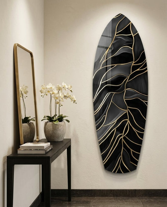 Black and gold leaf vein surfboard glass wall art on a cream wall beside a black console table with white orchids