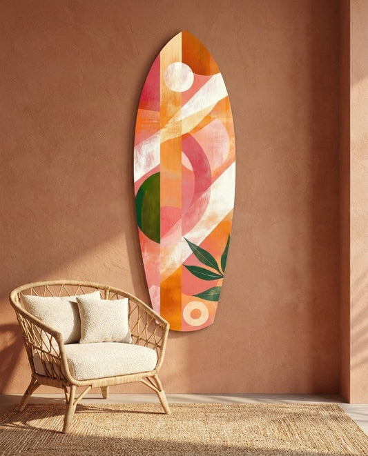 Coral geometric surfboard glass wall art on a terracotta wall above a rattan chair with cream cushions