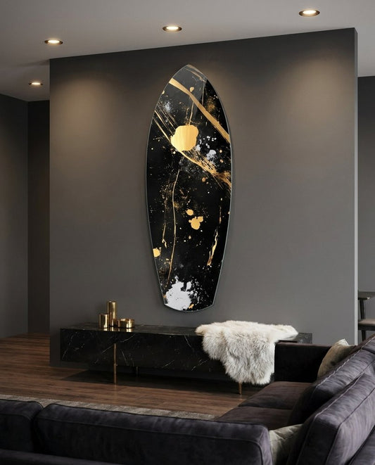 Black and gold splatter surfboard glass wall art on a gray wall above a black console and a charcoal sofa
