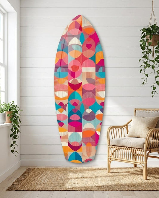 Pink and Teal Half Circles surfboard glass wall art in a white shiplap room beside a rattan armchair and hanging plants