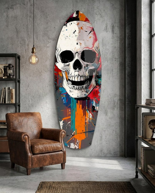 Paint drip skull surfboard glass wall art on a gray concrete wall above a brown leather armchair