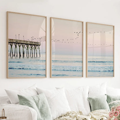 Pink ocean sunset wall art set of 3 with a wooden pier, waves, and seagulls