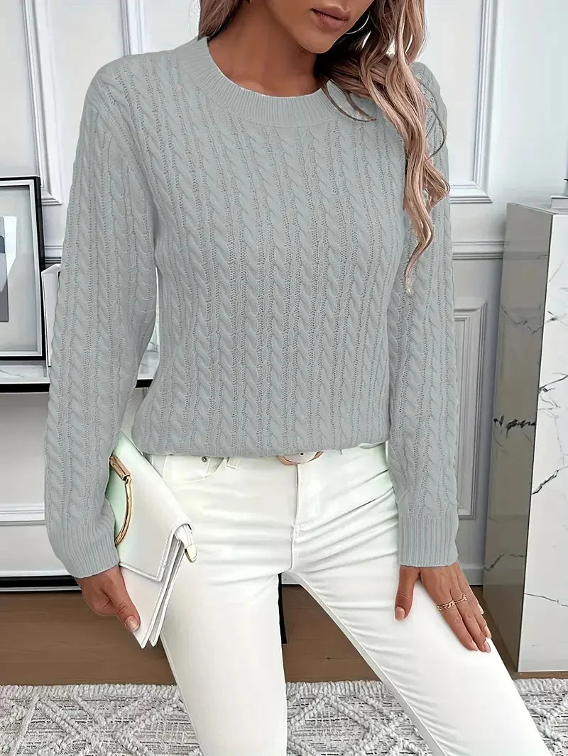 Silver Gray women’s cable-knit pullover sweater styled with a clutch in a chic interior