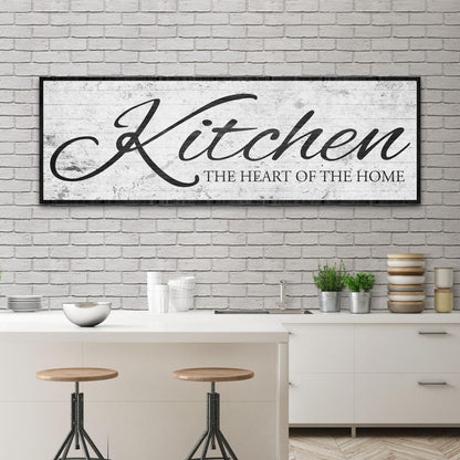 White distressed canvas sign with the word Kitchen in black script and a black border above a kitchen island with stools