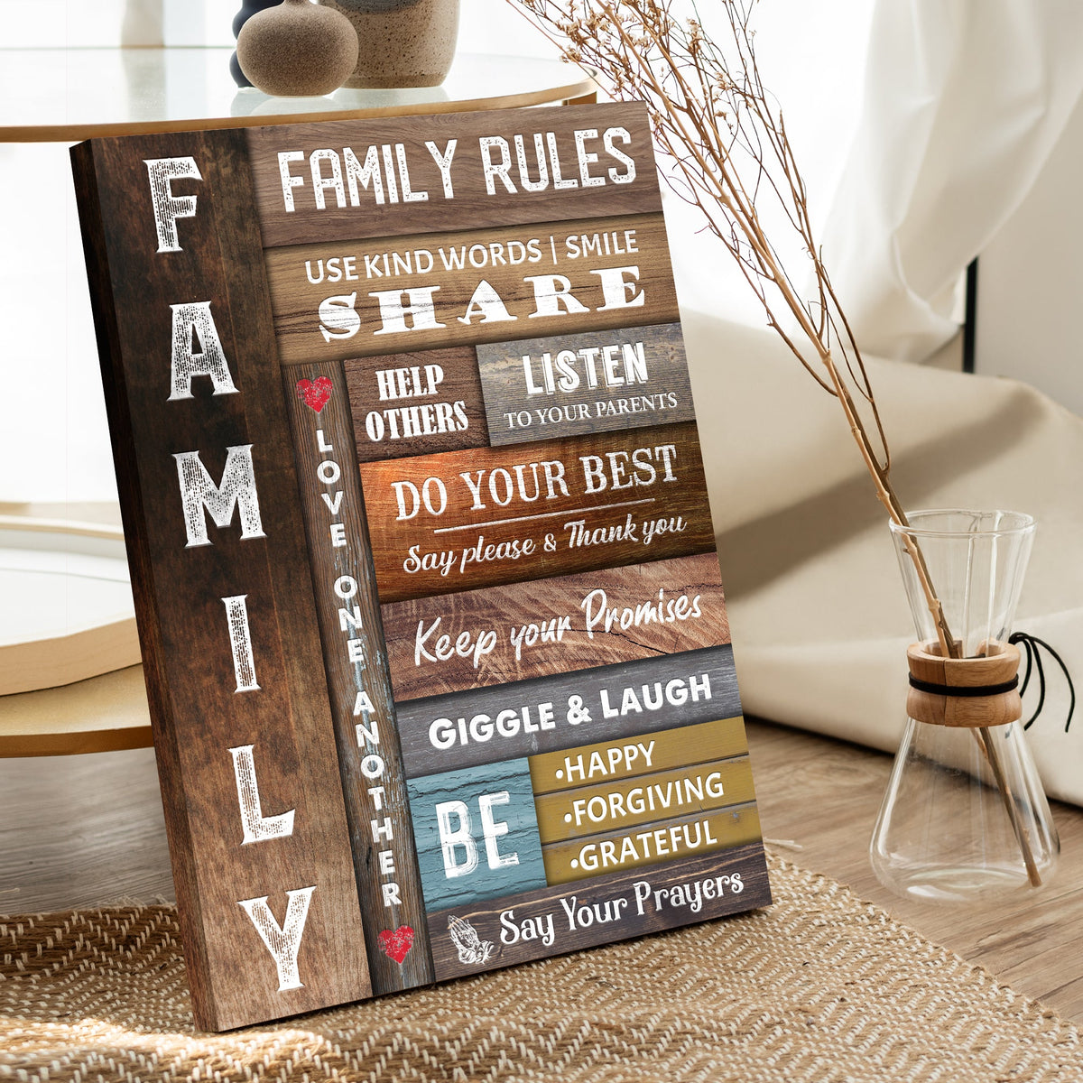 Family Rules canvas sign leaning on a woven rug beside a glass vase, seen at an angle
