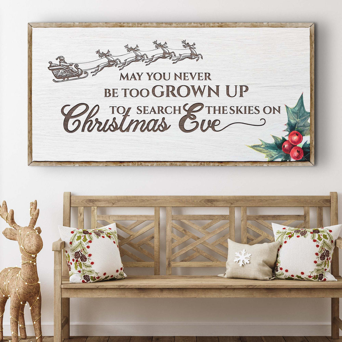 Second style of the Christmas Eve sign in white with a gray sleigh and holly, above a wooden bench with pillows
