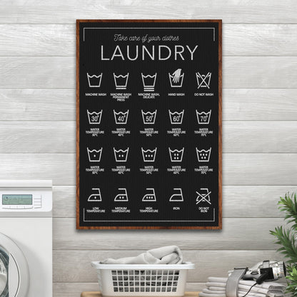 Laundry Care Symbols Guide canvas in Style 2, black with white symbols, on a gray plank wall above a basket