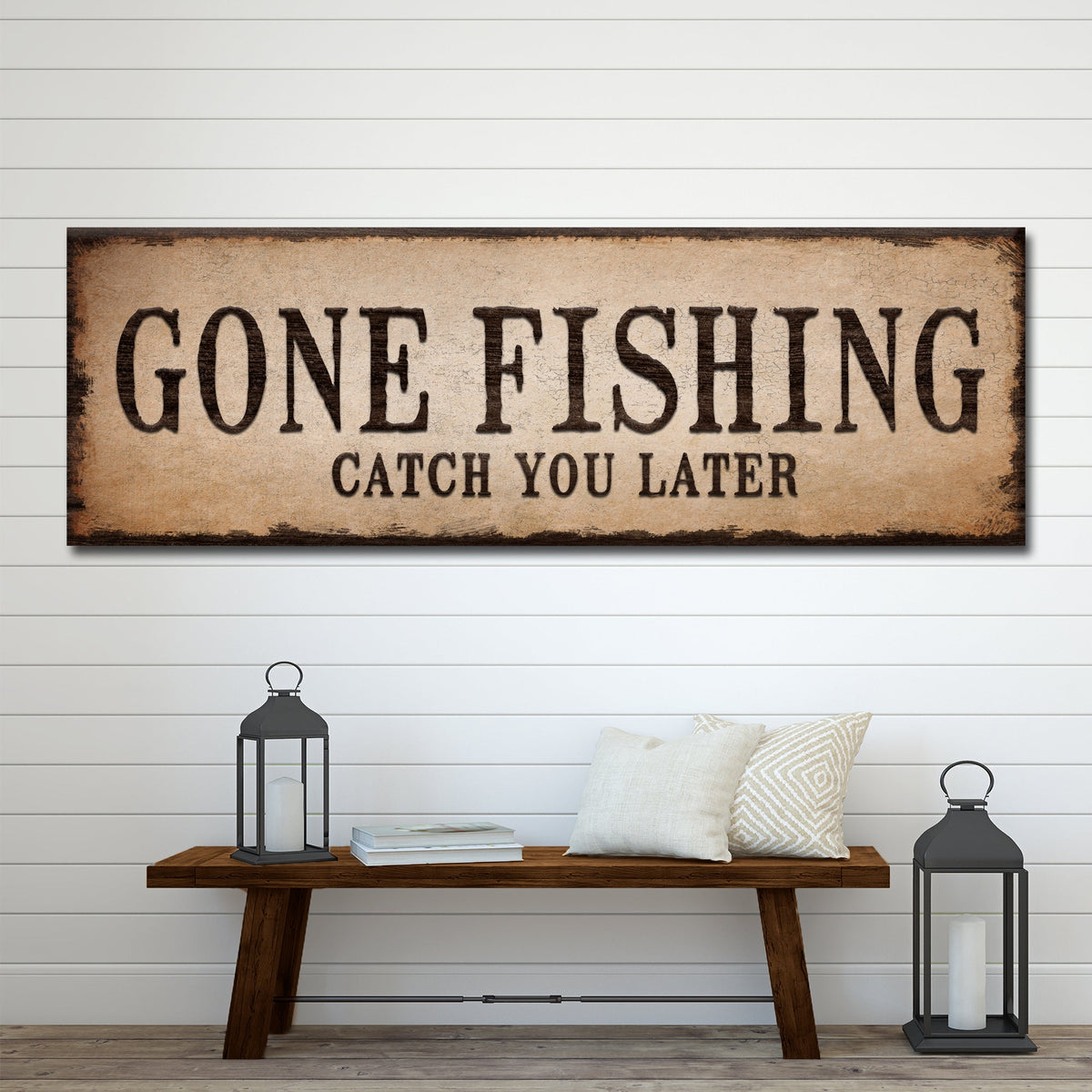 Long tan canvas sign with dark block letters reading Gone Fishing, Catch You Later, above a wood bench with lanterns