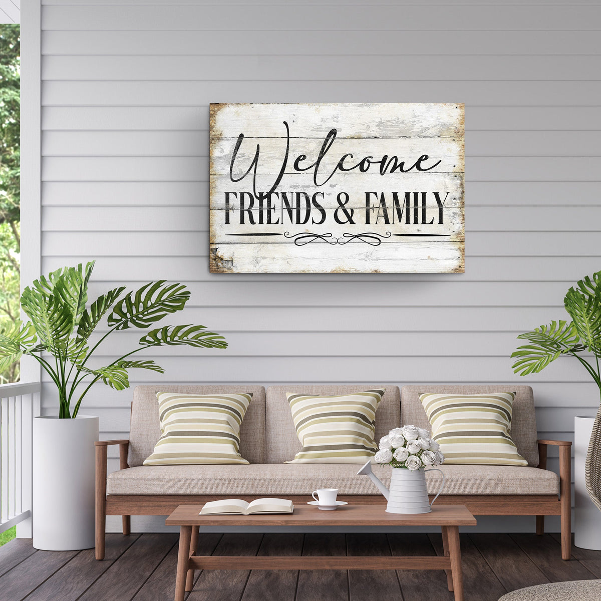 White wood-look Welcome Friends and Family canvas sign in black script on gray siding above a bench