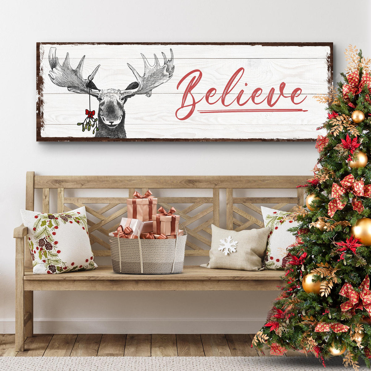 Believe canvas sign with a moose wearing holly on white wood-look planks, above a bench beside a Christmas tree