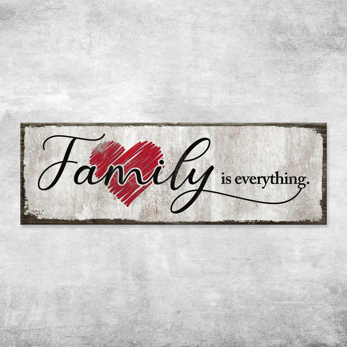 Family Is Everything canvas sign with a red heart shown close up on a pale gray concrete wall