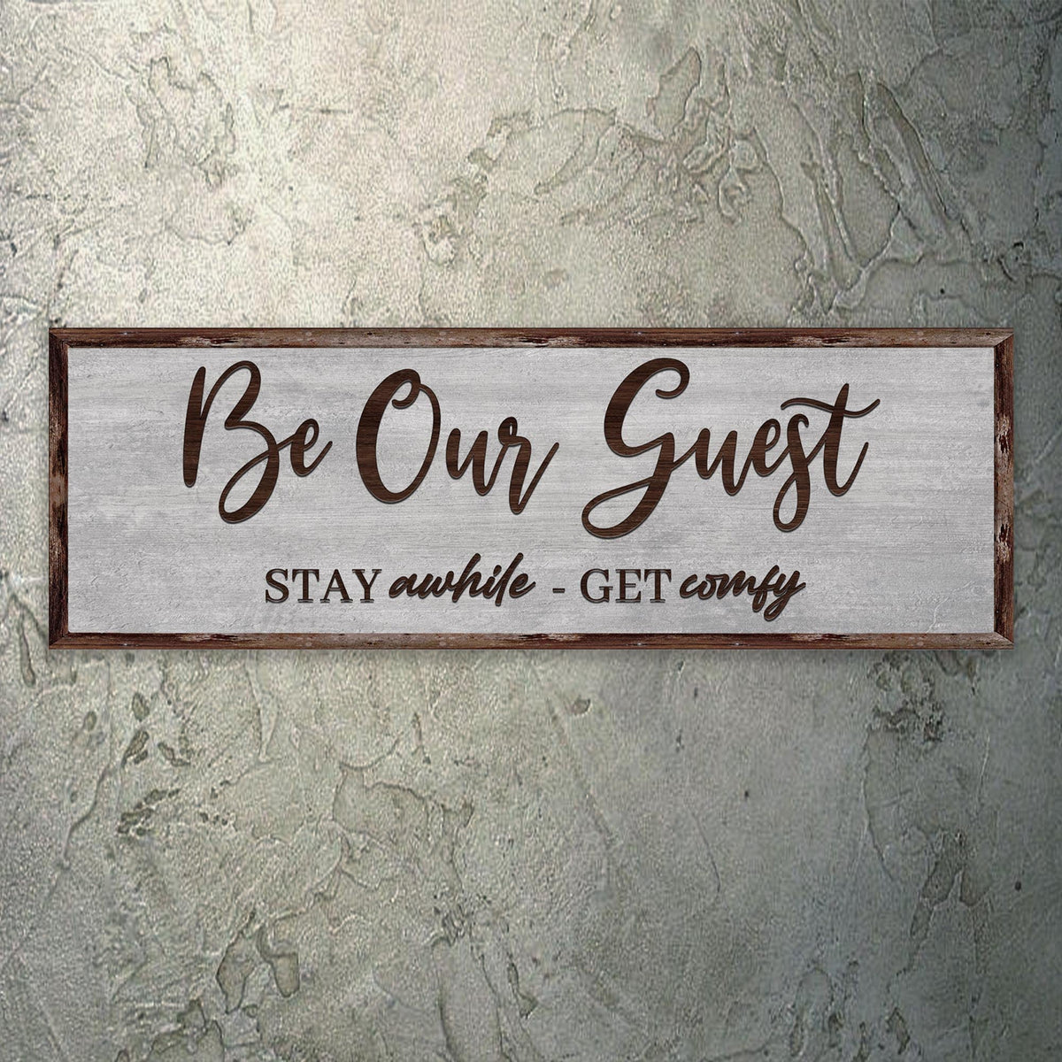 Be Our Guest Stay Awhile canvas hung on a gray plaster wall