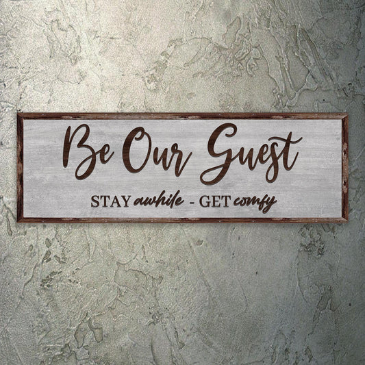 Be Our Guest Stay Awhile canvas hung on a gray plaster wall