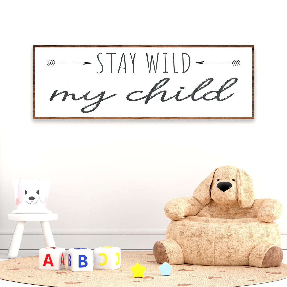 Stay Wild My Child canvas sign with two arrows on white, above a plush dog chair and toy blocks, nursery wall decor