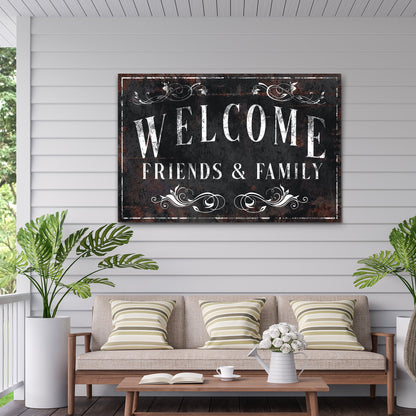 Black Welcome Friends and Family canvas sign on gray siding above a wooden bench with striped cushions