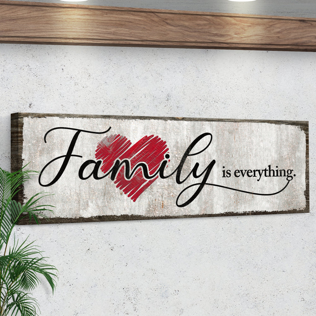 Family Is Everything canvas sign seen at an angle under a wooden shelf, showing the dark wrapped edge