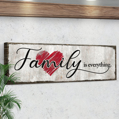 Family Is Everything canvas sign seen at an angle under a wooden shelf, showing the dark wrapped edge