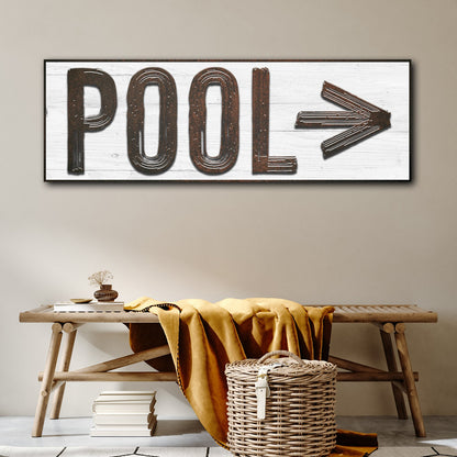White style of the pool arrow canvas sign with brown and gray lettering, hung above a wooden bench with a basket
