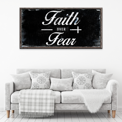 Style 2 of the Faith over Fear canvas sign in white script on a black distressed-look background above a gray sofa